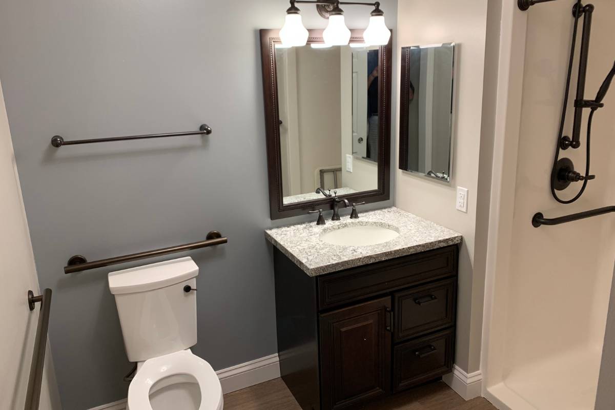 Private bathroom, with a toilet, small sink vanity, and step-in shower