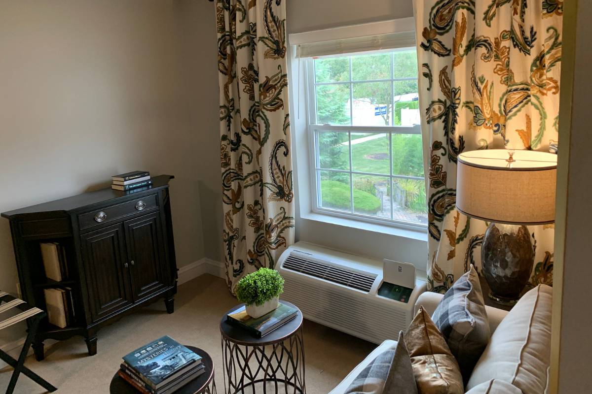 A model living room at Dresher Estates with a sofa, decorated with a lamp, curtains and a side tables