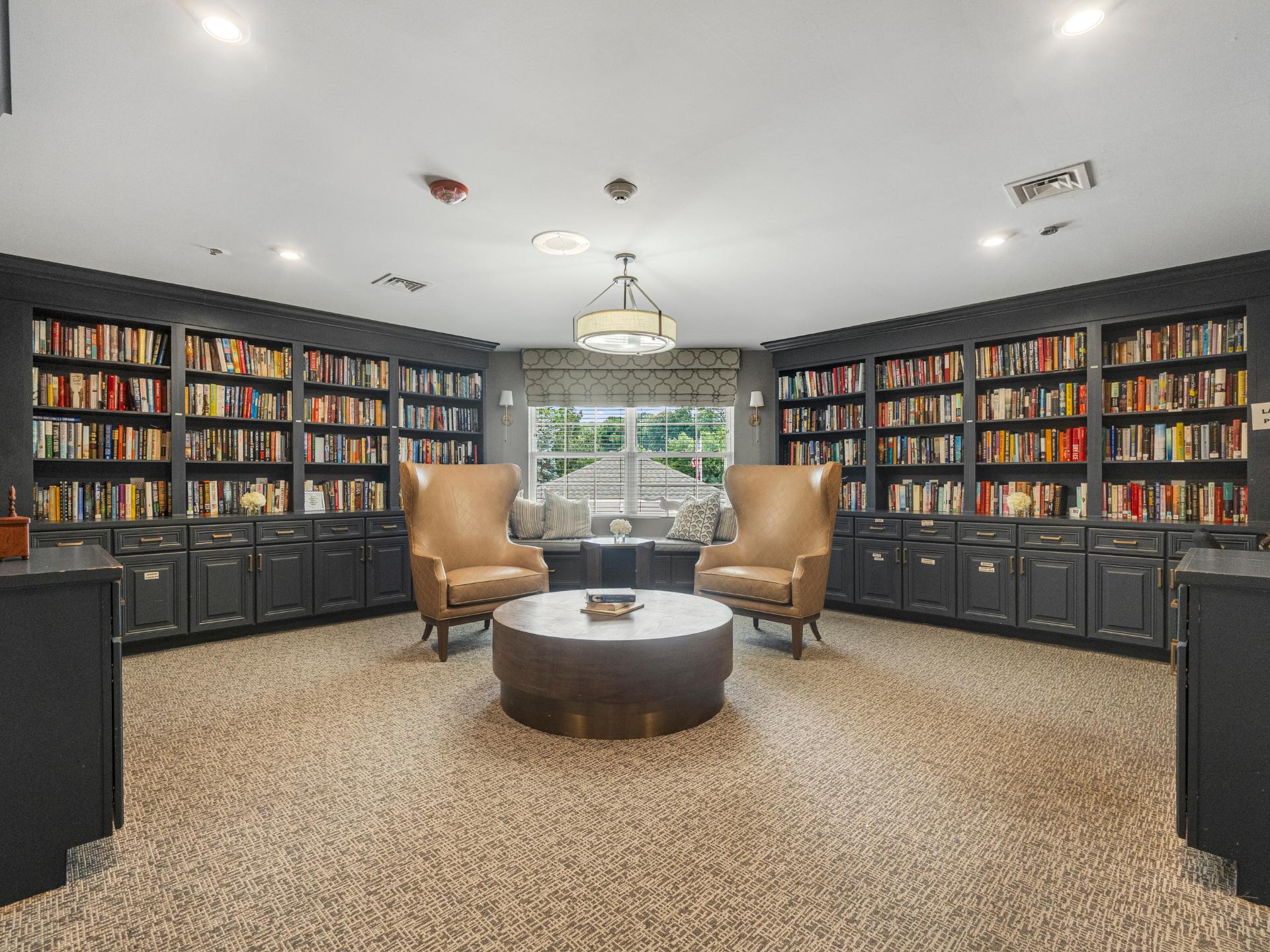 Walls lined with bookshelves, with two chairs and a tables to sit at
